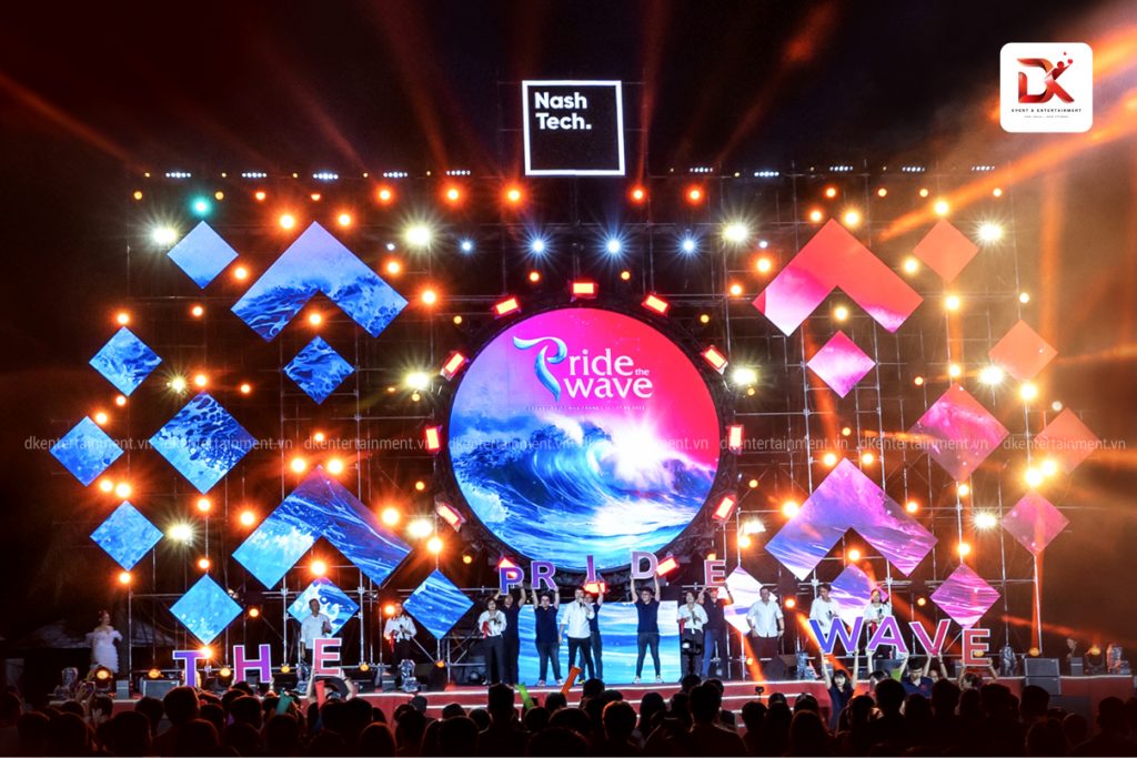 People cheering and dancing at a gala dinner with colorful lights, organized by an event agency in Ho Chi Minh.